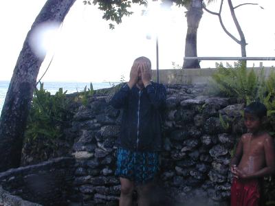 外シャワーを浴びる父、横に地元の少年