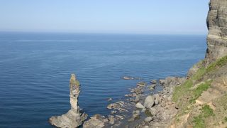 着物を着た女性が赤ん坊をおんぶして海を見つめている姿