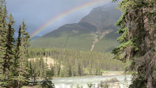 すさまじい水量が流れ落ちる滝。水しぶきで虹が。