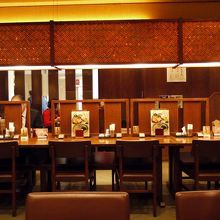 長いカウンターの周りにテーブル席が並んだ店内 