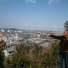 神社の高台からメリーゴーランドを指差す増田さん。