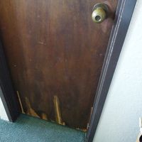 バスルームのドア。　合板木製ドアが荒れ果てています。