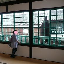 室内から外を眺める妻の図