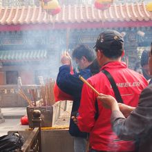 長い線香を持って熱心に祈る人々