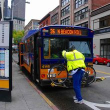 バスの先頭に自転車を載せる男性客