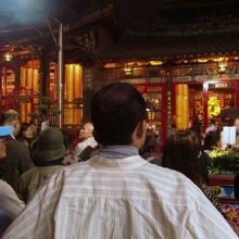 寺の奥でぐるぐる回る電飾、恐らく故人の名前を書いた札の集合体