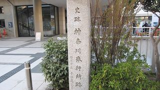 神奈川奉行所跡は県立青少年センター玄関脇にあり、石碑と金属プレートを嵌め込んだ案内があります。