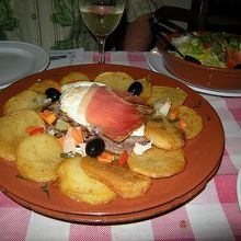 ビーフの上に目玉焼きと生ハム、焼いたジャガイモがのっている