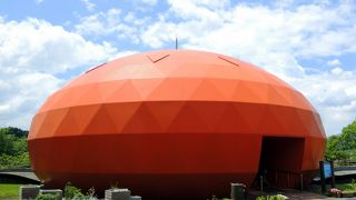 緑の畑の中にポツリとオレンジ色の柿ドームが目立つ