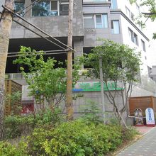 看板から植え込み越しに、ハナロマートのロゴが見えます。