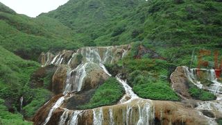 錆びた鉄色の斜面を流れる滝