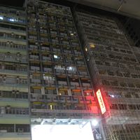 赤い看板の左側の古いビル（15階建て）