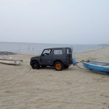 砂浜にたたずむボートと四駆車。