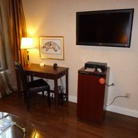 部屋の奥の窓側にあるデスクとテレビと有料の商品が入った冷蔵庫