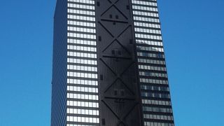 黒ガラス張りとＸの鉄骨外観、外広場で休憩。