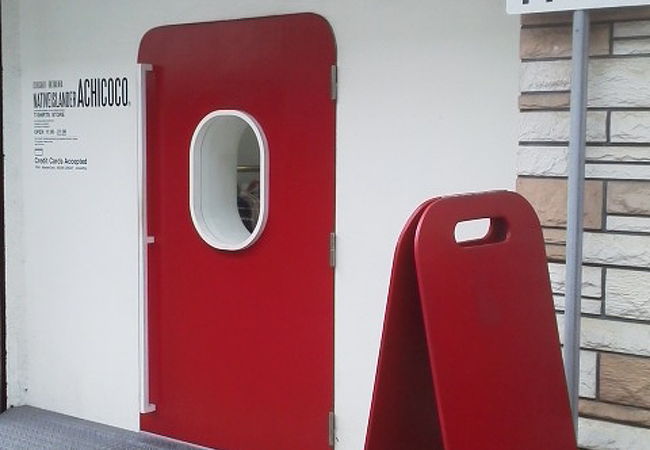 白色基調の雰囲気に赤色の扉が「ACHICOCO A STORE」～石垣～