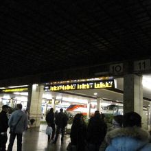 掲示板前で到着ホームが表示されるのを待つ人々