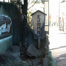 御門通りの歩道沿いに木の立て札と石碑があります。