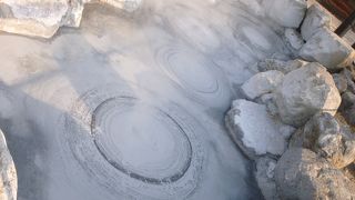 ぽこぽこと坊主の頭のような気泡が次々と現れる灰色の熱泥地獄