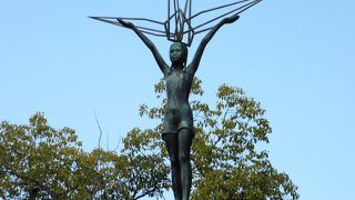 折り鶴の上に立つ少女の像。