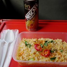 席にテーブルあります。車内で買ったナシゴレンと缶コーヒー