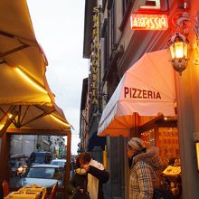 右のピザ店の奥に、黄色の看板があります。そこが薬局。