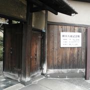 周りを大きなビルに囲まれた日本家屋