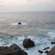 残照に輝く岩場の岩礁に打ちつける日本海の白波。