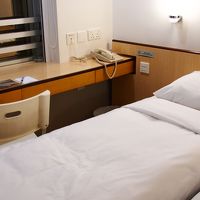 カウンターテーブルが荷物置き場に。ベッドは病院のように幅狭。