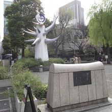 歩道沿いにある碑 (後方に見えるのは太陽の塔の小型版)