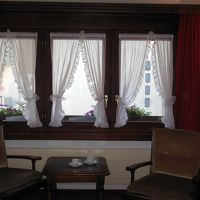 ベッドの脇のテーブルと椅子。カーテンの後ろがベランダ。