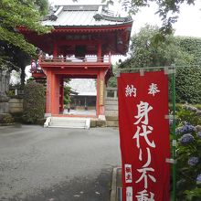 身代り不動尊の奉納旗と山門。山門は鐘楼門(明和8年)建立。