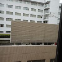 部屋の窓から。隣ビル屋上、フェンスあれど空調音響く