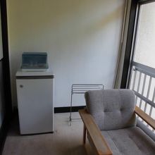 窓に面して2脚の椅子、冷蔵庫。懐かしい昭和の家族旅行のお宿。