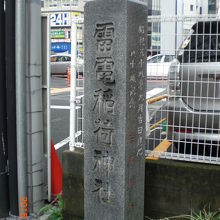 雷電稲荷神社の石碑と背景に見える甲州街道の様子です。