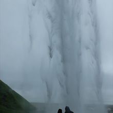 セリャラントスフォスの滝裏に立つカップルがシルエットになる。