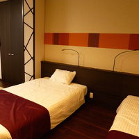 和洋室。シックな色合いの木を基調にした板張り床にベッド+畳