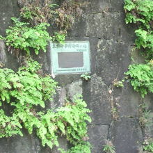 石垣の草の中、記念銘板が見えます。それほど大きくはありません