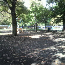 草地広場の様子です。広いスペースに遊具や樹々があります。