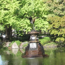 緑の樹々を背景にした鶴の噴水の銅像です。