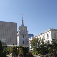 青空の下塔頂になびく三越マークの旗