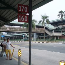クランジ駅のバス停、向こうに見えるのは駅舎！