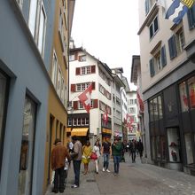 この通りを進んで，一番手前の白い建物の1Fにあります。