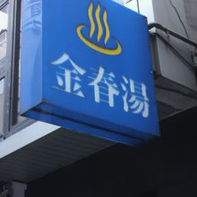 青色の看板に、湯のマークと金春湯の字が鮮やかに描かれています