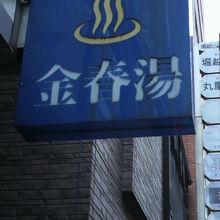 金春ビルの北側に青色の看板が掲げられています。入口は左側です