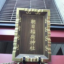 朝日稲荷神社の鳥居に掲げられた額と背景の建物の様子です。