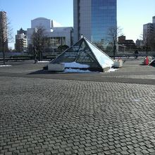 広い広場に、ピラミッド型のモニュメントと遠くのビルが映えます