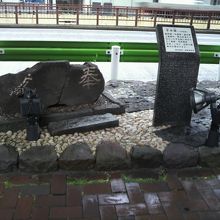 手水鉢と解説板の様子です。背景の道路は、昭和通りです。