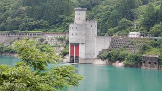 エメラルドグリーンの湖面、中世のお城を思わせる発電所、赤い橋