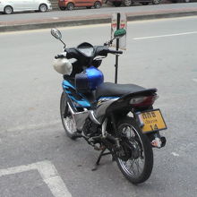 バイクタクシーのドライバーは、朝食で、バイクから離れています